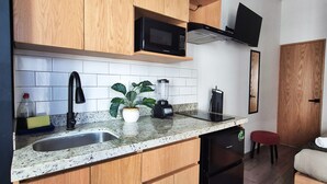 A modern kitchen with wooden cabinets, a microwave, a blender, and a sink. - Lofts La Paz (Guadalajara)