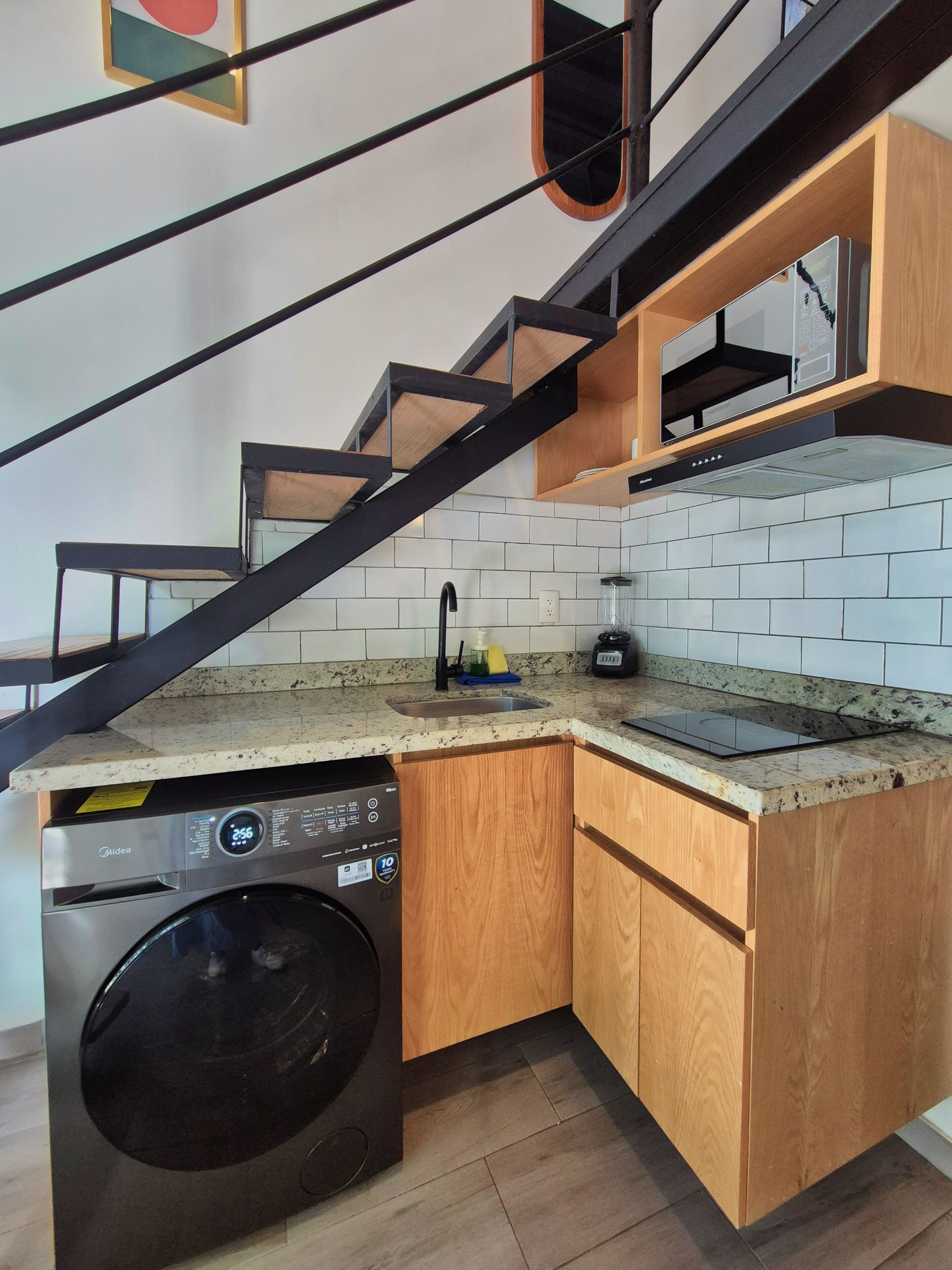 A compact kitchen with a built-in washer, a stainless steel dishwasher, and a wooden countertop.