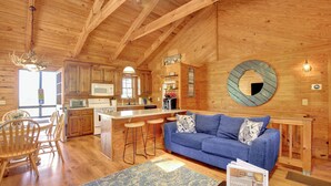 A wooden cabin interior with a kitchen, dining area, and living room.