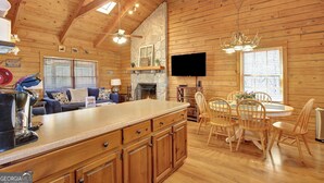 A wooden cabin interior with a kitchen, dining area, and living room.