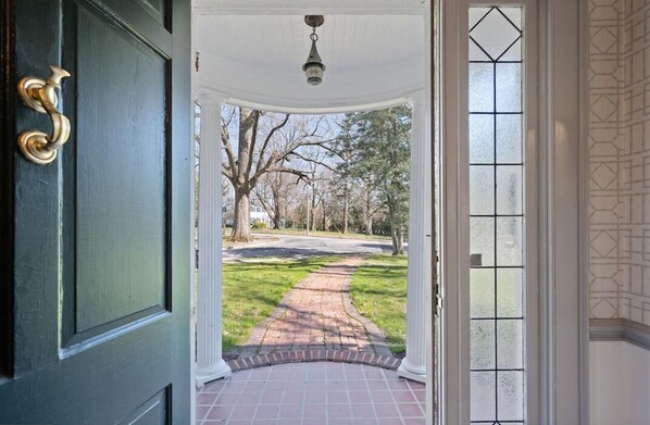 A covered entryway with a brick pathway leading to a street.