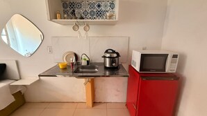 A compact kitchen with a sink, a stove, a microwave, and a red cabinet.
