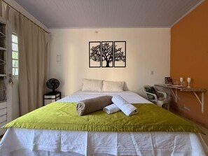 A hotel room with a bed, a fan, a table with glasses, and a wall art piece. - Caminito Brasilia Hotel (Luziânia)