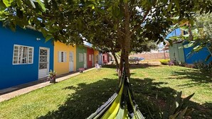 A colorful building with a grassy yard, a hammock, and a tree.