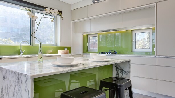 A modern kitchen with green accents, white cabinets, and a marble countertop. - Spacious 2-bed Apartment Close to City (Sydney)
