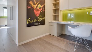 A modern kitchen with a large poster, white cabinets, and a white chair. - Spacious 2-bed Apartment Close to City (Sydney)