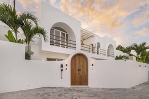 Un edificio moderno con una puerta de madera grande, ventanas arqueadas y un balcón.