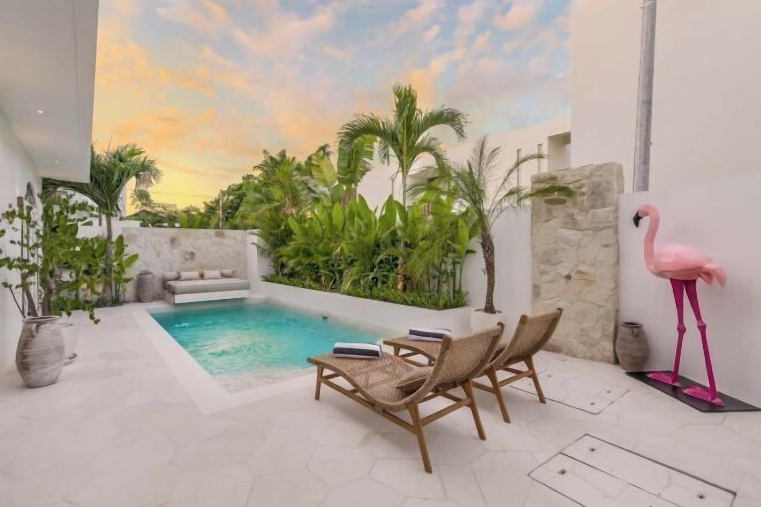 Un espace piscine avec des chaises longues et une statue de flamant rose.