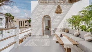 A modern outdoor living area with a white wall, wooden bench, and a thatched ceiling. - Villa Las Casas 2 by BaliSuperHost (Bali)