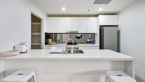 A modern kitchen with white cabinetry, a stainless steel sink, and a built-in oven. - The Skyline Stopover - Near Sydney Airport (Mascot)