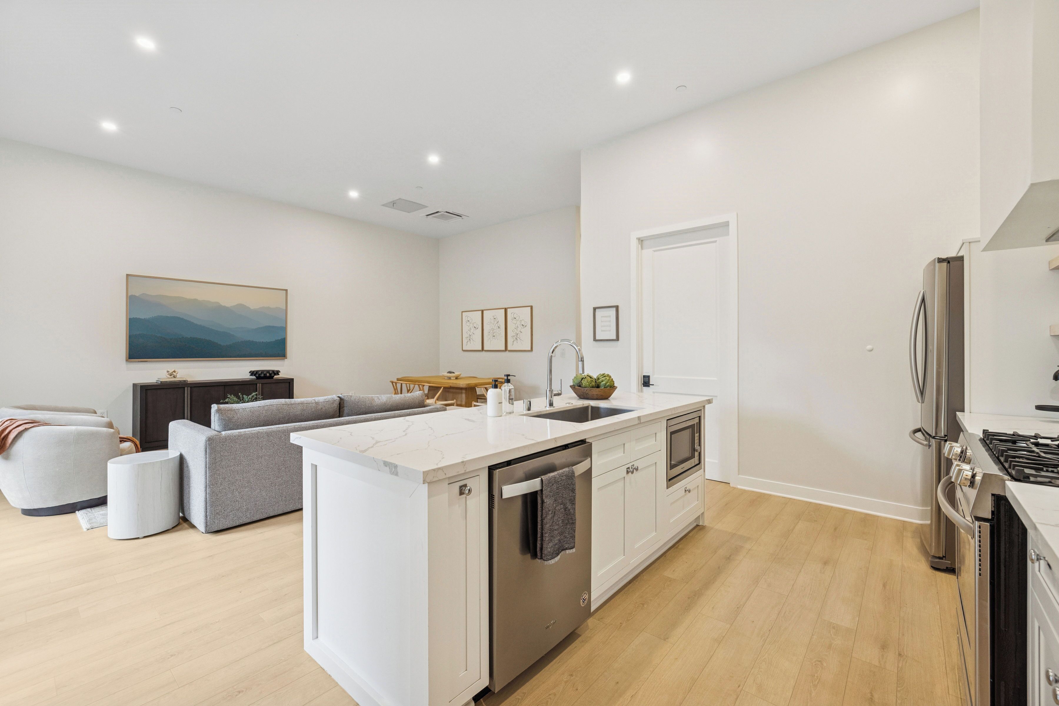 Cocina moderna con una isla central, electrodomésticos integrados y comedor con sofá y mesa.