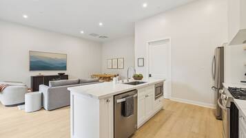 Cocina moderna con una isla central, electrodomésticos integrados y comedor con sofá y mesa.