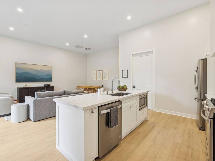 A modern kitchen with a central island, built-in appliances, and a dining area with a sofa and table.