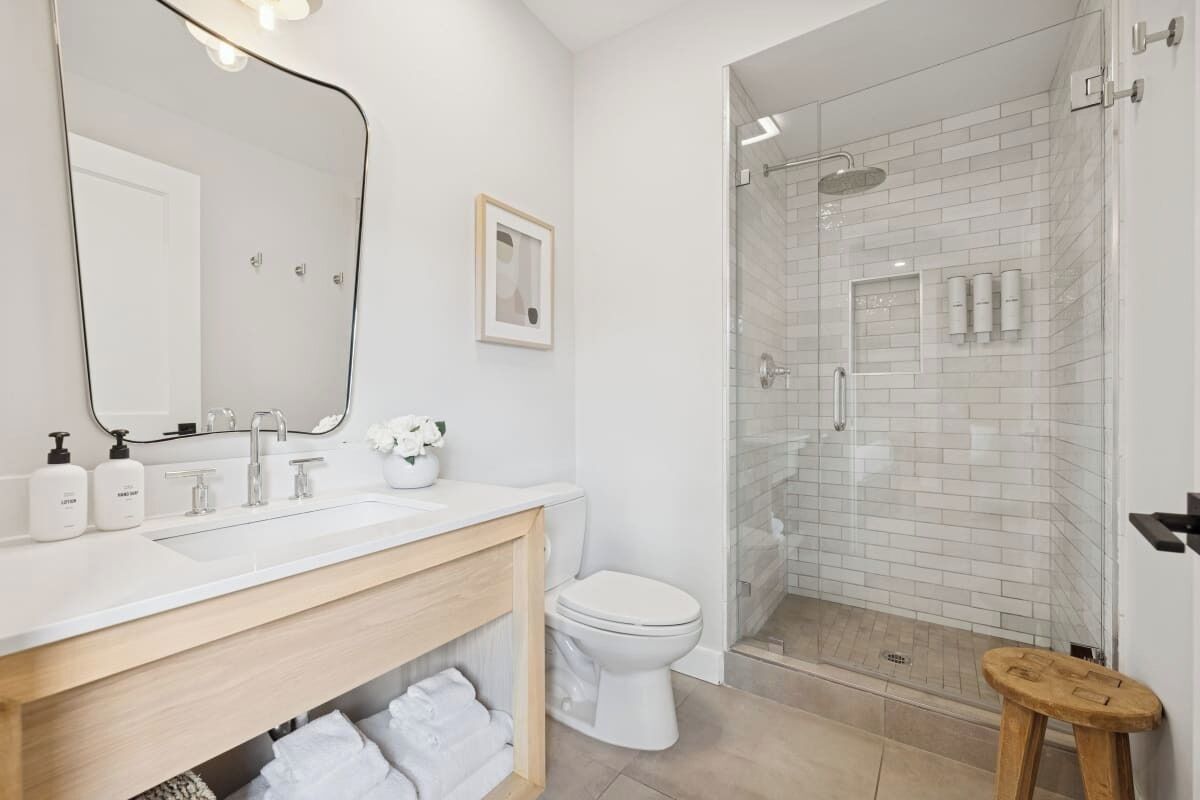 A modern bathroom with a white sink, mirror, and toilet.