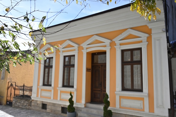 A building with a yellow facade, white trim, and a central entrance door.