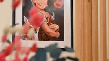 A framed photograph on a wall, a wooden staircase, and a plant with red flowers.