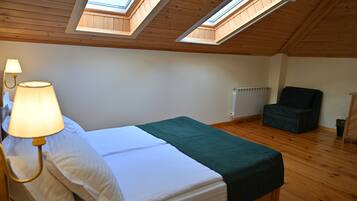 A room with a bed, a chair, a lamp, and skylights.