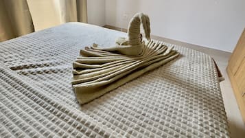 Una habitació d'hotel amb un llit, aire condicionat fixat a la paret i una finestra amb cortines.