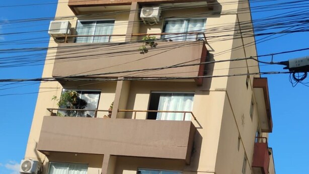 A multi-story building with balconies, air conditioning units, and a gated entrance. - Residencial Gomes (Goiânia)