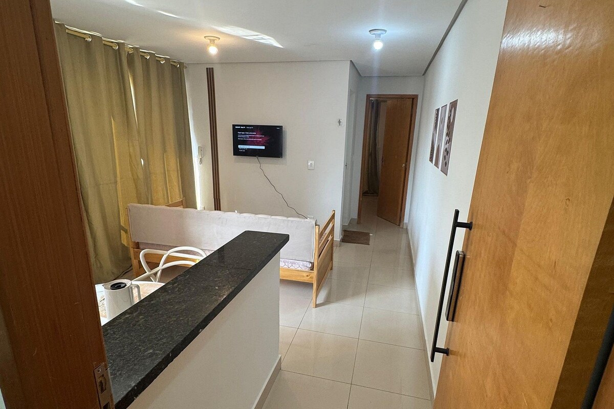 A compact living space with a kitchenette, a bed, a TV, and a door with a number.