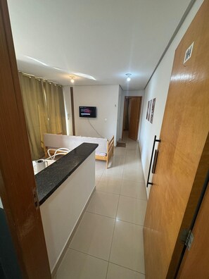 A compact living space with a kitchenette, a bed, a TV, and a door with a number.