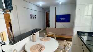 A modern kitchen with white cabinets, a black countertop, and a dining area with a round table and four chairs. - Residencial Gomes (Goiânia)