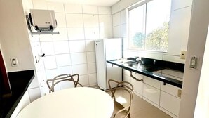 Eine moderne Küche mit einem runden Tisch, Stühlen, einem Kühlschrank und einem Fenster, das für natürliches Licht sorgt.