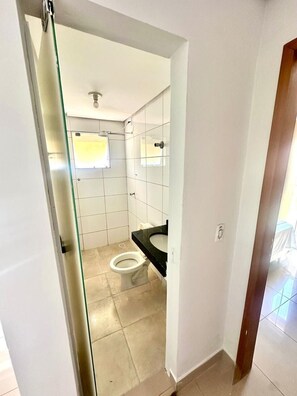 A small, compact bathroom with a toilet, sink, and shower. - Residencial Gomes (Goiânia)