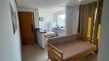 Un espacio habitable compacto con cama, kitchenette y comedor.