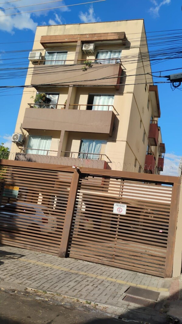 A multi-story building with balconies, air conditioning units, and a gated entrance.