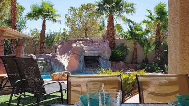 An outdoor patio with a pool, chairs, and a rock formation. - Little Paradise in Las Vegas with Pool (Las Vegas)