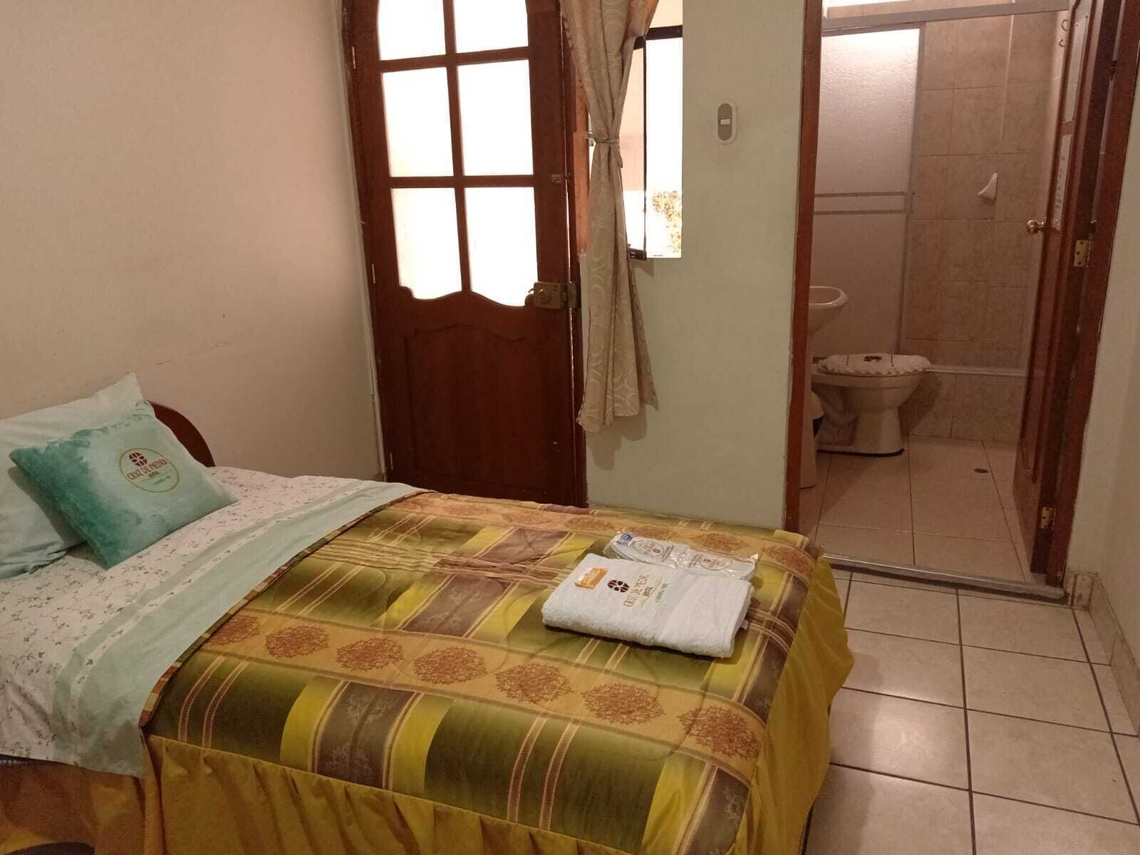 A bedroom with a bed, a door, and a bathroom visible through an open door.