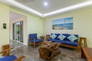 Uma sala de estar com um sofá azul, mesa de centro de madeira e uma janela grande.
