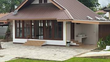 A modern house with a sloped roof, large windows, and a paved patio.
