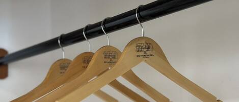 Un porte-manteaux en bois avec des cintres étiquetés « DE HOM HOTEL ».