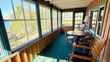 Una habitación con un ventanal grande, una mesa con sillas y una mecedora.