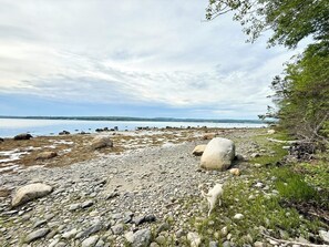 En klippefyldt kystlinje med udsigt over vandet og fjerne kyster.