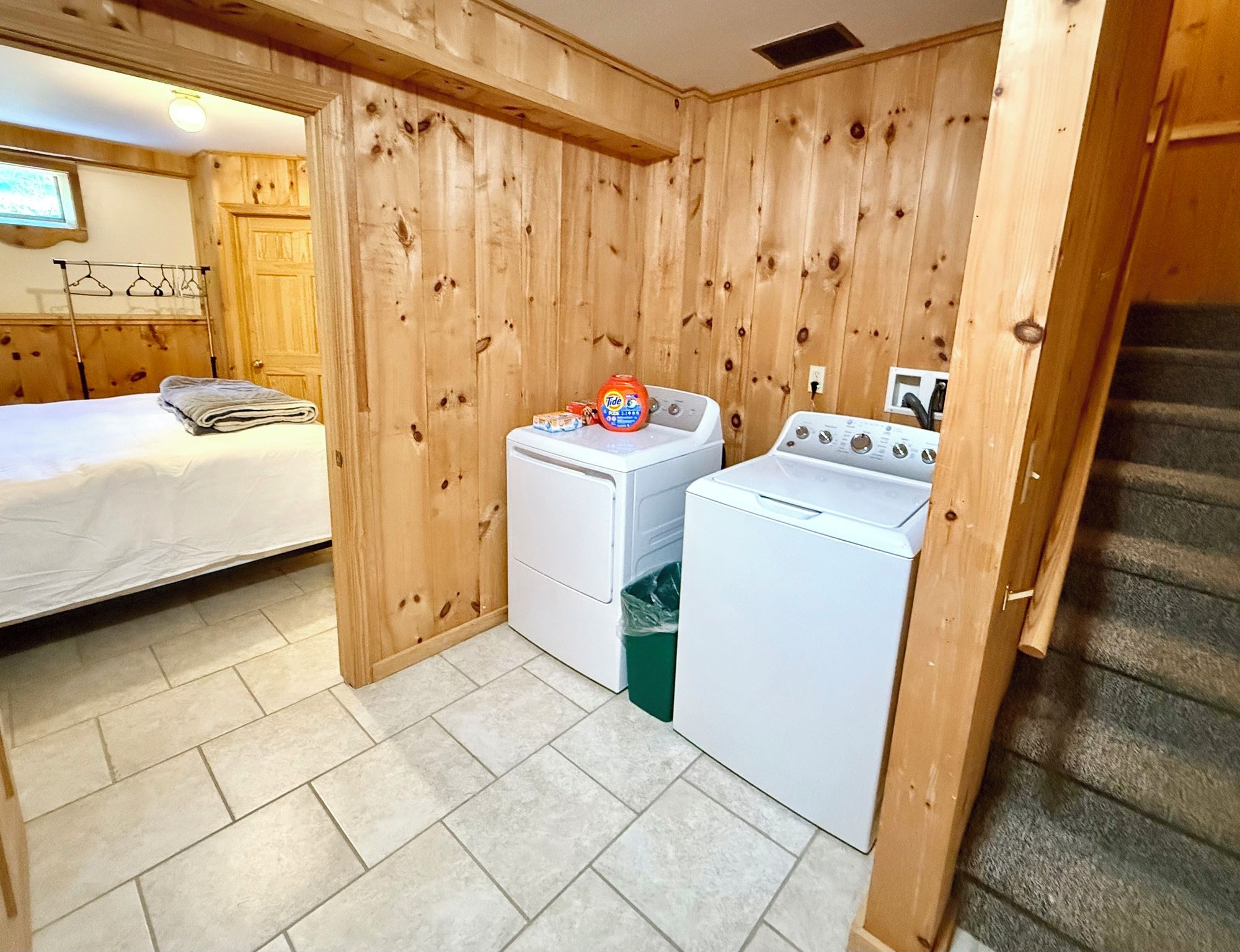 A compact room with a bed, a washing machine, and a dryer.