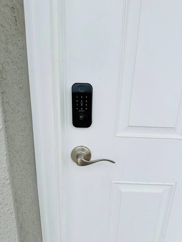 A white door with a modern electronic keypad lock and a keyhole.
