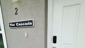 Un numéro de maison, le chiffre « 2 », et une enseigne indiquant « The Cascade », le tout sur un mur à texture.