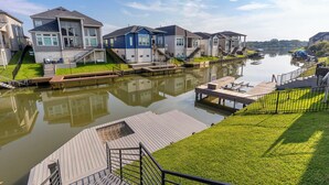 A residential area with houses along a calm water body, featuring grassy areas and wooden docks.