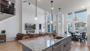 A spacious kitchen with a large island, modern pendant lighting, and a view to the outdoors.