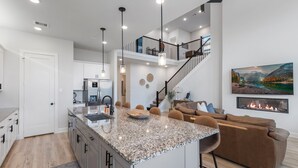 A modern kitchen with granite countertops, a central island, and a dining area with bar stools.