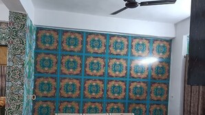 A room with a patterned wall, a ceiling fan, a sofa set, and a patterned floor. - Shri Premanand Ji Niwas Sthan (Vrindavan)
