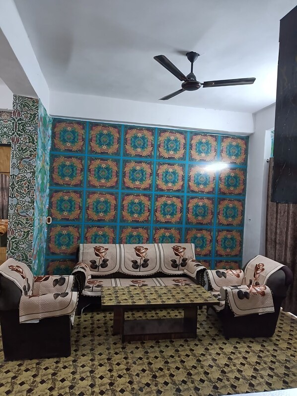 A room with a patterned wall, a ceiling fan, a sofa set, and a patterned floor.