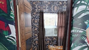 A narrow hallway with patterned walls and a bed with a floral bedspread. - Shri Premanand Ji Niwas Sthan (Vrindavan)