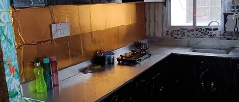 Een koelkast, een oven, een kookplaat, kookgerei, borden en bestek