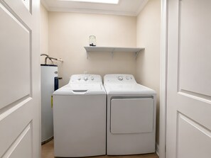A laundry room with two stacked front-loading washers and a single dryer.