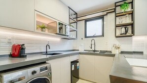 Una cucina moderna con lavatrice integrata, lavello e finestra sopra il piano di lavoro.