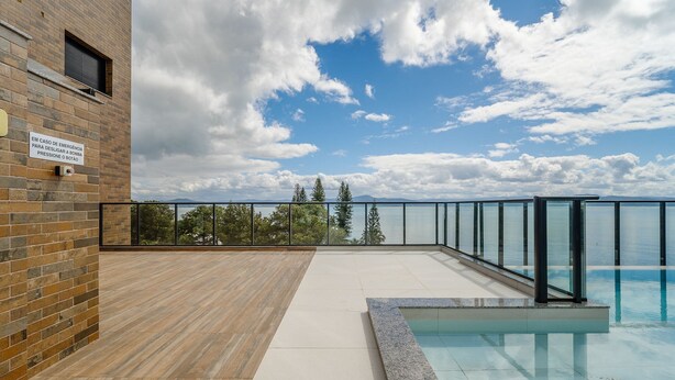 Area piscina sul tetto con vista aperta sul cielo e sugli alberi.